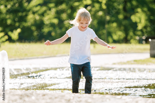 Obraz na płótnie Cute cheerful girl playing in fountain. Kid in white shirt having fun in summer park w salonie
