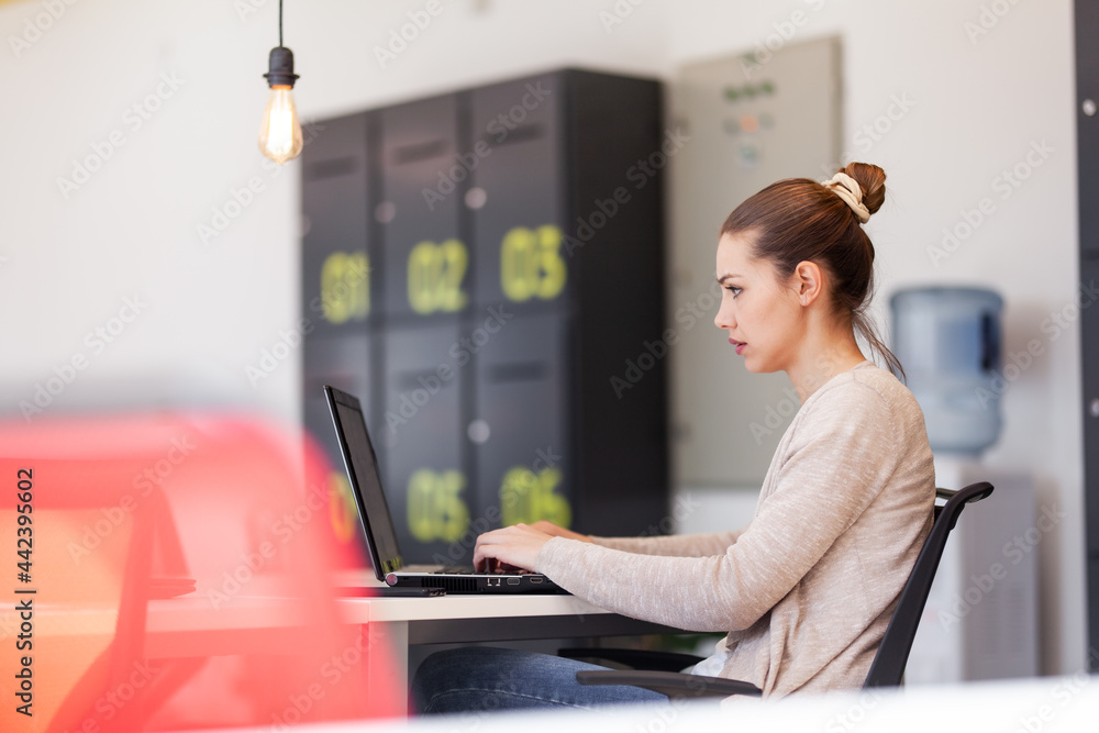 Beautiful girl working on a laptop in a modern coworking space. Successful businesswoman in an office Beautiful girl working on a laptop in a modern coworking space. Successful businesswoman in an office