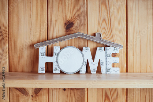 On the background of wooden boards inscription Home with a roof over the words. Cozy photo of an imitation of a house on a wooden background photo