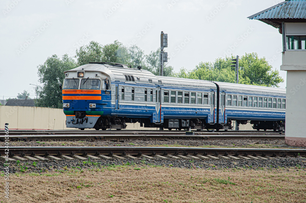 An old diesel passenger follows the rails against the backdrop of a morning summer steppe landscape. An old diesel passenger follows the rails against the backdrop of a morning summer steppe landscape.