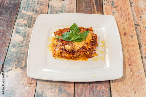 Lasagna recipe with gluten-free pasta, grated cheese, tomato, beef stew and basil leaves