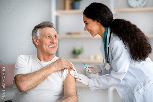 Fotografie Millennial doctor making medical drug injection or anti-covid vaccine to disable
