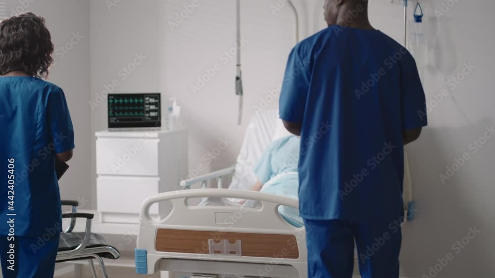 Caring african ethnic medical team at the bedside of an elderly male patient. Caring health care providers monitor vital signs of an elderly male hospital patient Caring african ethnic medical team at the bedside of an elderly male patient. Caring health care providers monitor vital signs of an elderly male hospital patient
