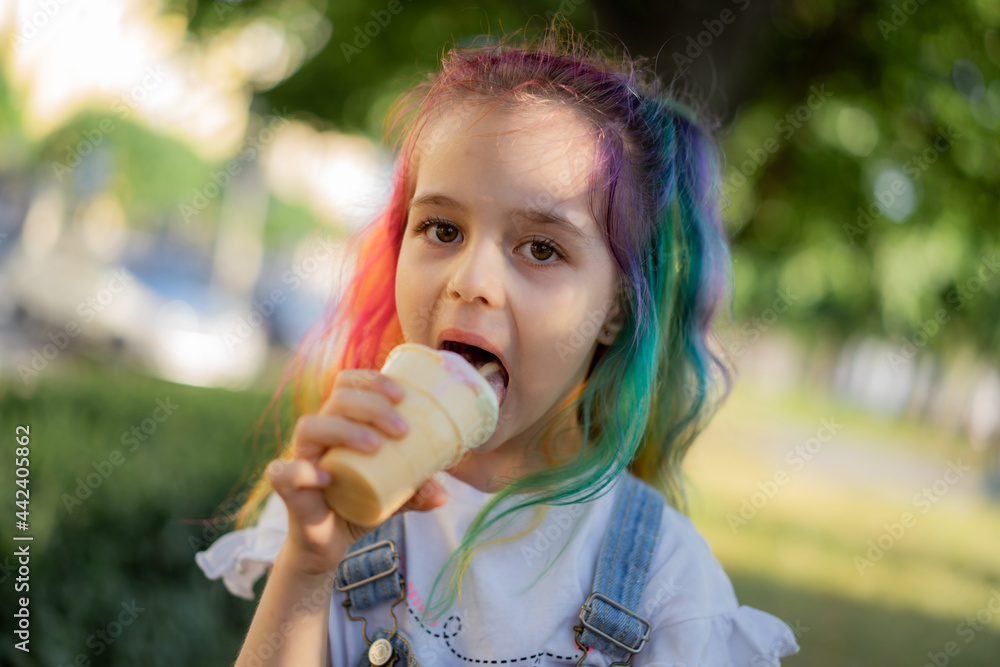 Happy little girl with colorful dyed hair eating ice cream outdoors in park. Image with selective focus Happy little girl with colorful dyed hair eating ice cream outdoors in park. Image with selective focus