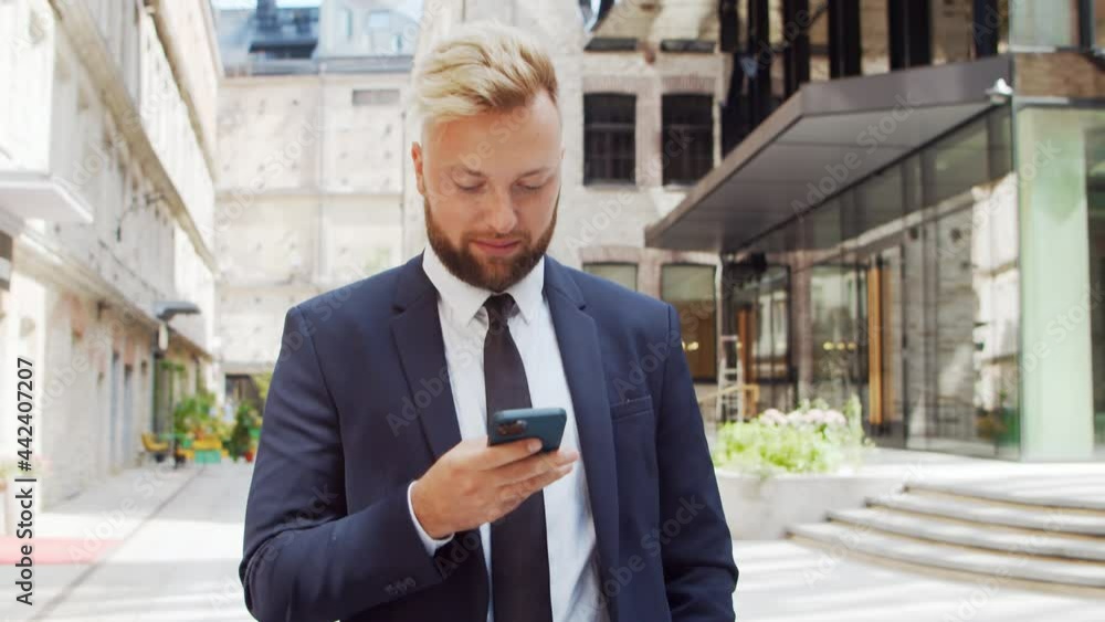 Confident businessman in front of modern office building. Financial investor is using smartphone outdoor. Banking and business.