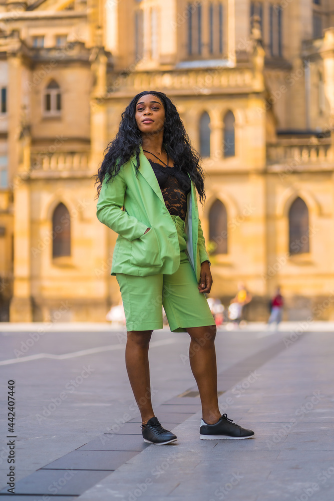 Fototapeta premium Lifestyle of a young girl of black African ethnicity with a beautiful green suit. Sightseeing in the city