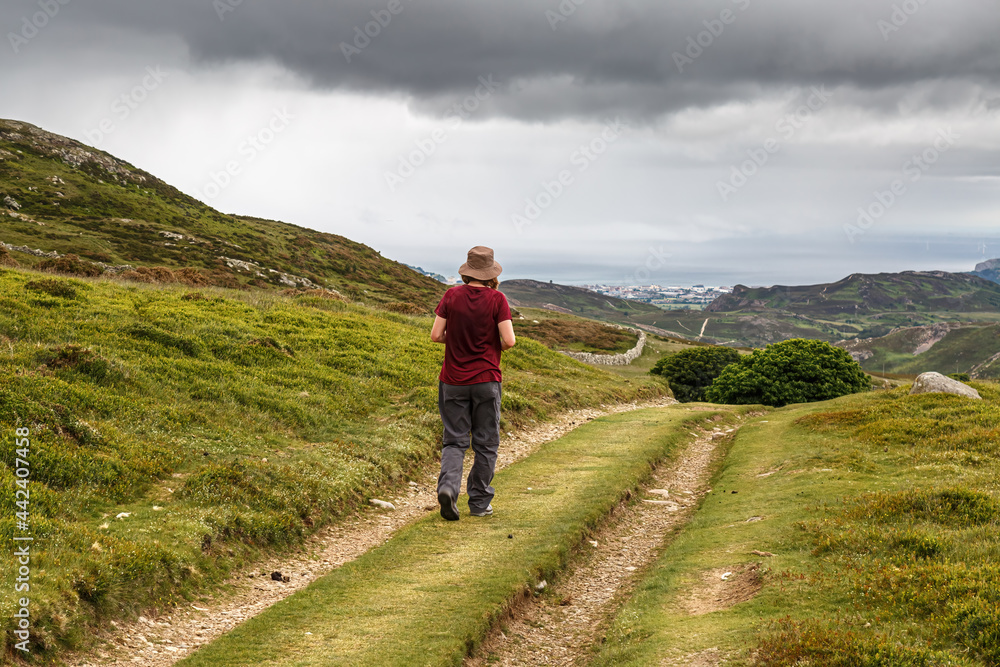A single female on a ramble along the mountain track on the scenic Wales Coastal Path at Penmaenmawr, Cony, Wales