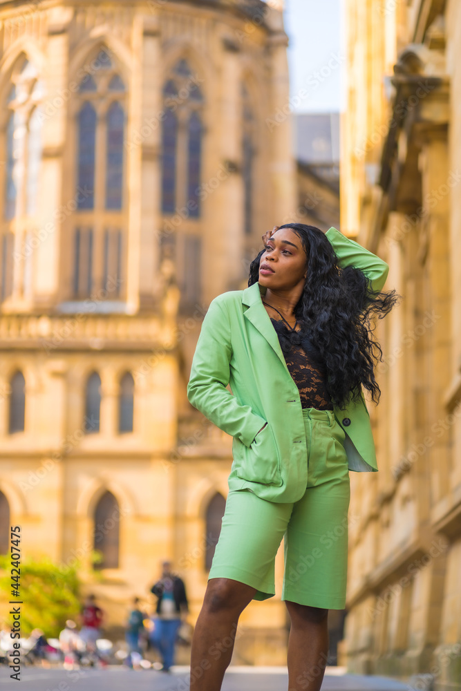 Lifestyle of a young girl of black African ethnicity with a beautiful green suit. Tourist perched in the city walking next to a cathedral