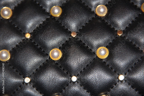 Shiny pearl buttons on a black leather surface. Backgrounds