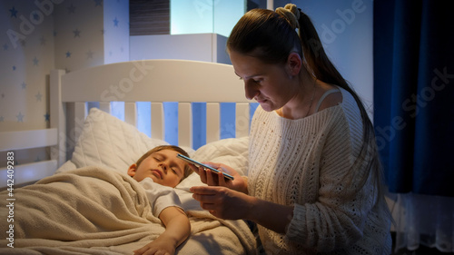 Young worried mother calling doctor by phone at night. Concept of children illness, disease and parent care