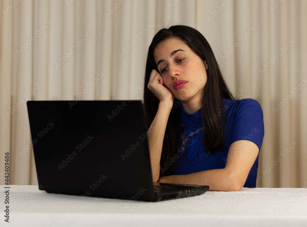 Woman sitting in front of her laptop. staring at the screen, bored, sleepy, tired. Latin woman in front of her laptop without spirits. Woman sitting in front of her laptop. staring at the screen, bored, sleepy, tired. Latin woman in front of her laptop without spirits.