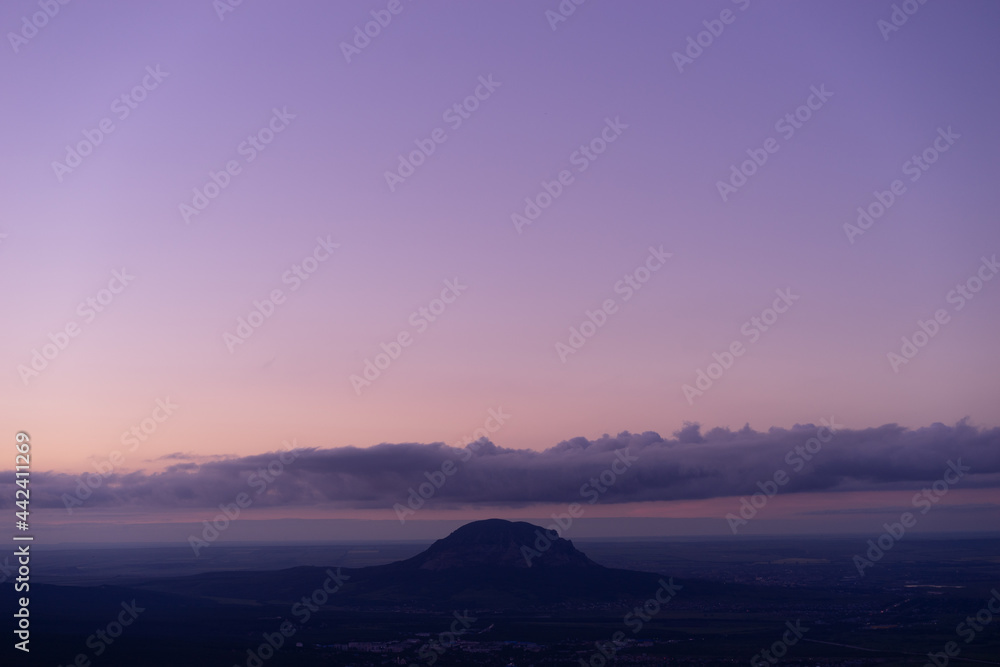 Sunset landscape of high mountain peaks under vibrant colorful evening sky.