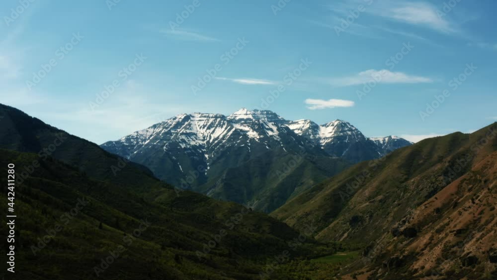 Stunning aerial drone view of famous Utah Mount Timpanogos with snow peaks and luscious green foliage below near Provo, UT on a warm sunny summer day. Stunning aerial drone view of famous Utah Mount Timpanogos with snow peaks and luscious green foliage below near Provo, UT on a warm sunny summer day.