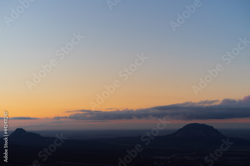 Sunset landscape of high mountain peaks under vibrant colorful evening sky.