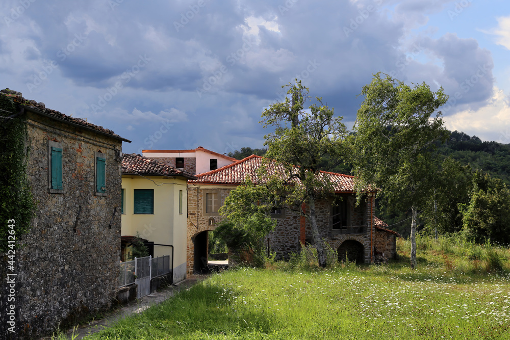 View of a small village in Tuscany countryside against a suggestive cloudscape. Pian di Cerreto, near Castelnuovo Garfagnana - Italy. View of a small village in Tuscany countryside against a suggestive cloudscape. Pian di Cerreto, near Castelnuovo Garfagnana - Italy.