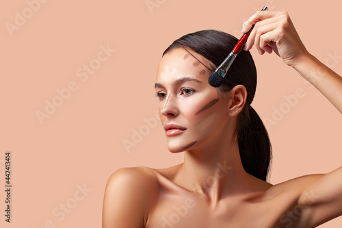 Makeup beauty. Portrait of a beautiful young woman brunette with smooth skin and fresh makeup. Applying makeup product, contouring and highlighting lines of cheekbones and chin. makeup angle of youth 