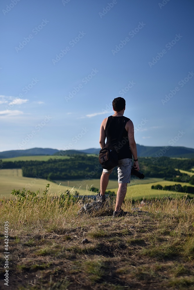 photographer man standing on top of a hill and looking at the landscape