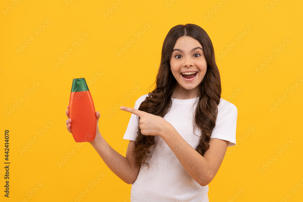 amazed teen girl with long hair pointing finger on shampoo bottle, promotion amazed teen girl with long hair pointing finger on shampoo bottle, promotion