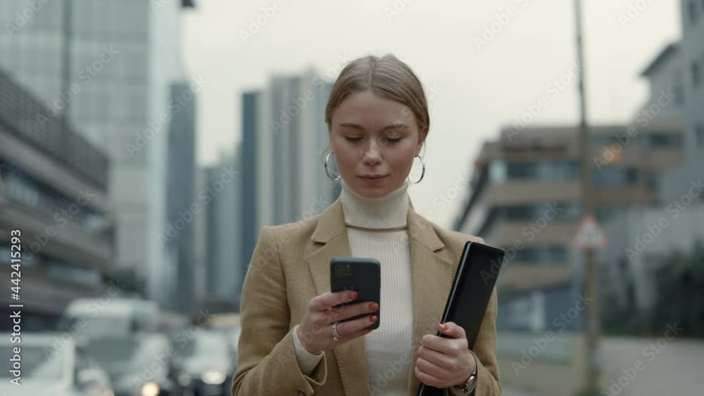 Business woman walking outdoors with clipboard and mobile Business woman walking outdoors with clipboard and mobile