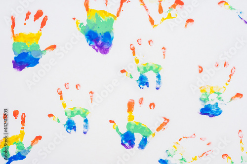 Child handprints of rainbow colors, on white sheet of paper. Top view