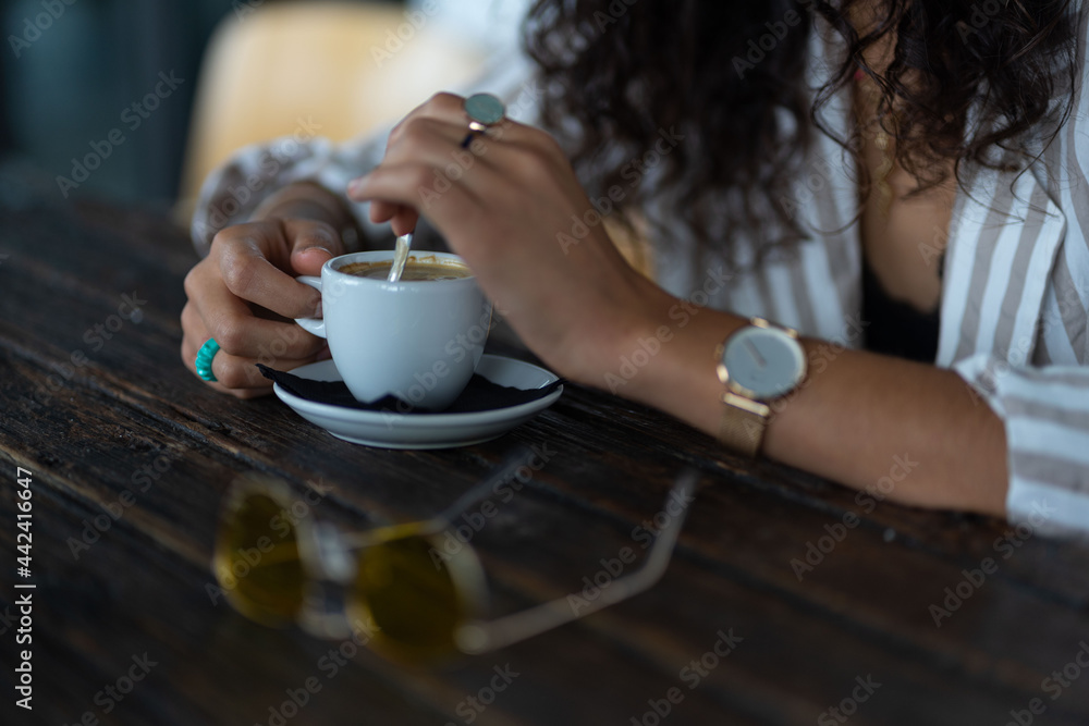 woman with rings and watch having a cup of coffee at wooden table woman with rings and watch having a cup of coffee at wooden table