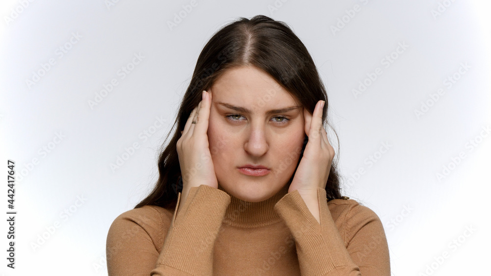 Portrait of young woman suffering from headache rubbing her head with hands Portrait of young woman suffering from headache rubbing her head with hands