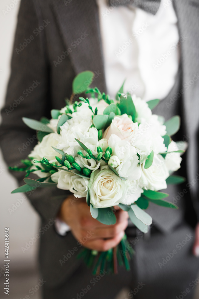 Beautiful man, groom holding big and beautiful wedding bouquet with flowers Beautiful man, groom holding big and beautiful wedding bouquet with flowers
