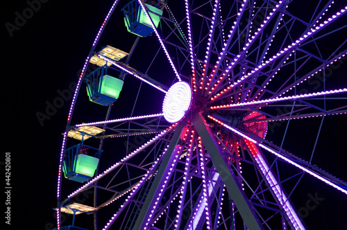 Looking up at lighted Blue Ferris Wheel against night sky showing axle.