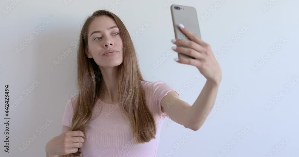 Cute Young Female In Casual Wear Posing At Mobile Phone Camera, Smiling, Enjoy Natural Beauty, No Make-up On Face. Caucasian Lady With Long Hair, Side View. Isolated White Background. Copy Space Cute Young Female In Casual Wear Posing At Mobile Phone Camera, Smiling, Enjoy Natural Beauty, No Make-up On Face. Caucasian Lady With Long Hair, Side View. Isolated White Background. Copy Space
