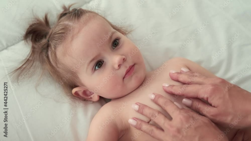 Childcare at Home, Child Protection, New Life, Leisure with Baby. Mom strokes the child who lies on the bed and looks at her Childcare at Home, Child Protection, New Life, Leisure with Baby. Mom strokes the child who lies on the bed and looks at her