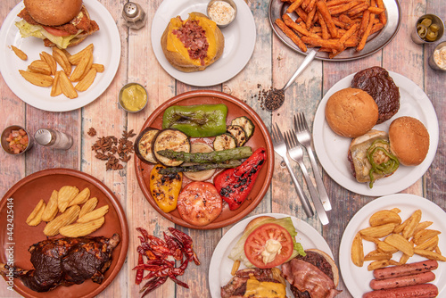 Set of Mediterranean dishes with hamburgers, sweet potato chips, grilled vegetables and asparagus, chicken with barbecue sauce and deluxe fries