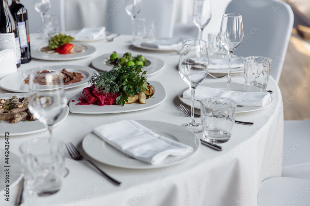 Table setting for a banquet or celebration. Empty wine glasses for spirits, champagne and juice. Set the table. Cloth napkins on a platter. Banqueting hall. Cold appetizers and salads.