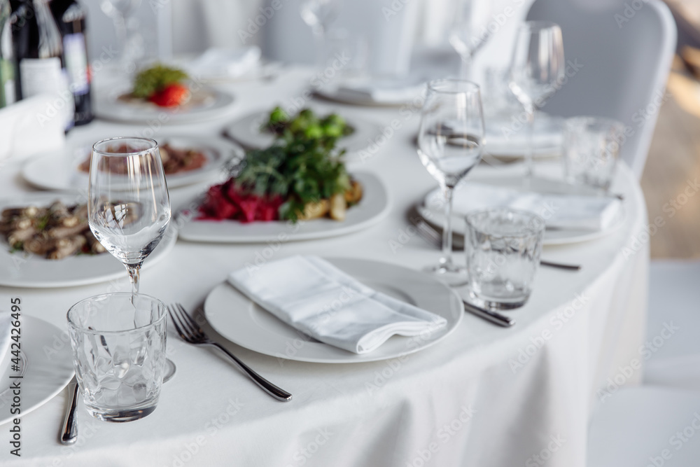 Table setting for a banquet or celebration. Empty wine glasses for spirits, champagne and juice. Set the table. Cloth napkins on a platter. Banqueting hall. Cold appetizers and salads.