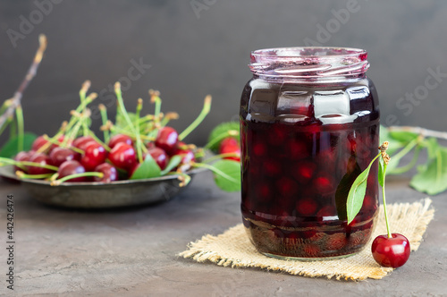 Sour cherry jam in glass jar with fresh raw sour cherries