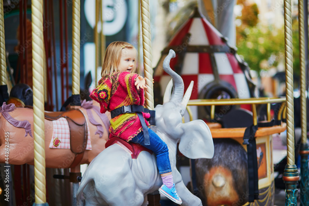 Toddler having fun on vintage French merry-go-round in Paris, France