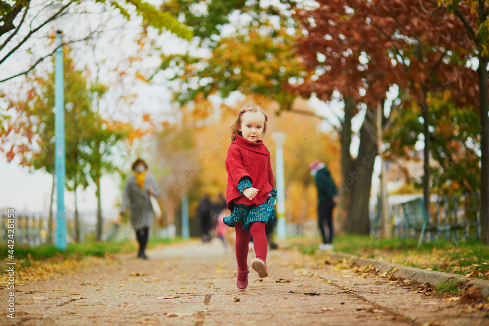 Fototapeta premium Adorable toddler girl playing in autumn park in Paris, France