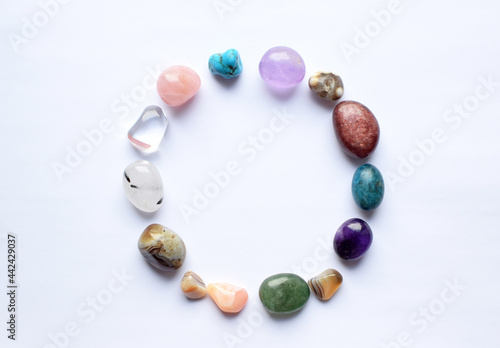 The circle is lined with natural minerals. Semi-precious stones of different colors, raw and processed. Amethyst, rose quartz, agate, apatite, aventurine on a white background.