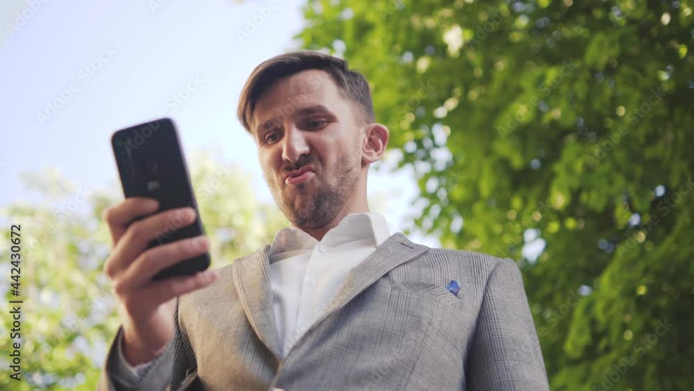 businessman stand in the city center street uses phone texting scrolling tapping smile technology communication sunny day success. An elegant man smiles. businessman stand in the city center street uses phone texting scrolling tapping smile technology communication sunny day success. An elegant man smiles.