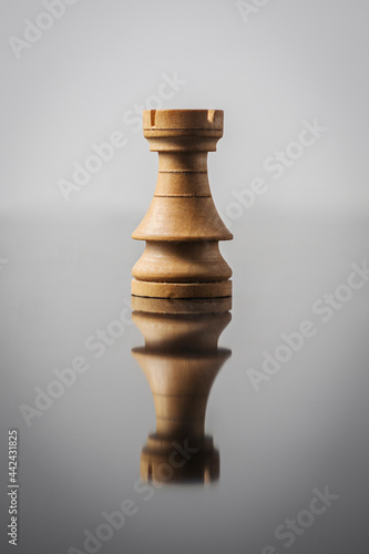 rook chess piece on white background with table reflection.
