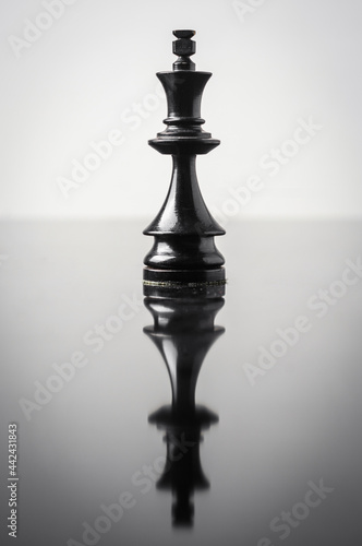the king chess piece on white background with reflection in table