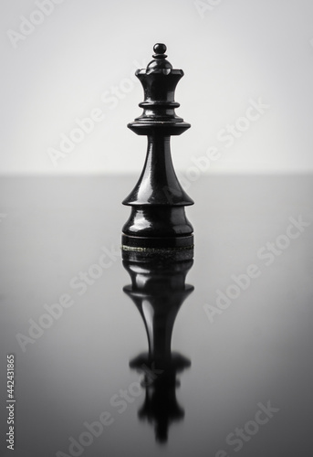 the queen chess piece on white background with reflection in table