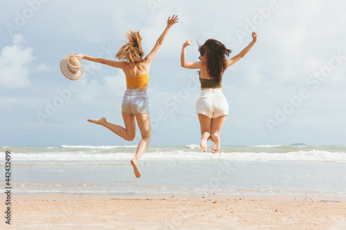 Two Asian women in summer casual clothes Jumping on the Beach Having Fun