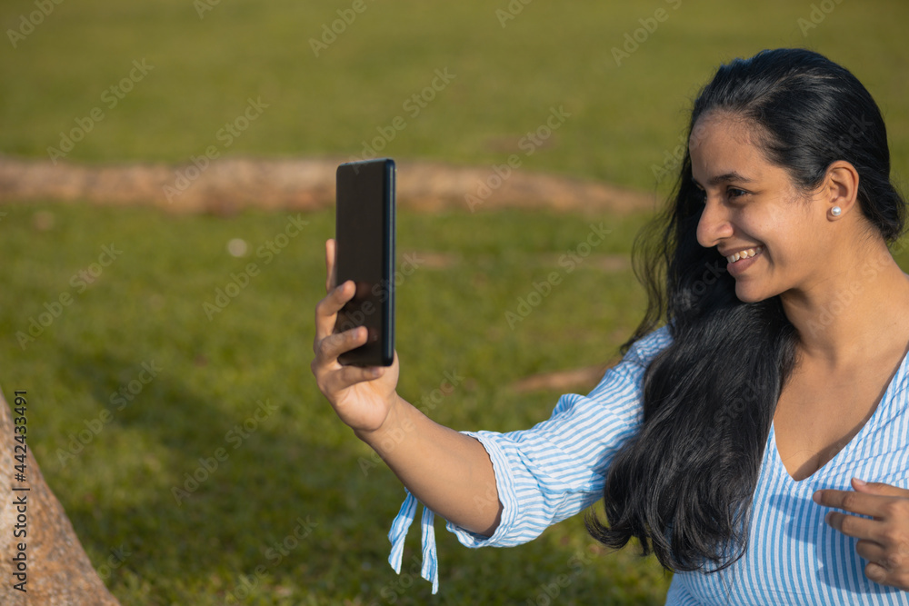 Latin woman taking photo with mobile in the green field Latin woman taking photo with mobile in the green field