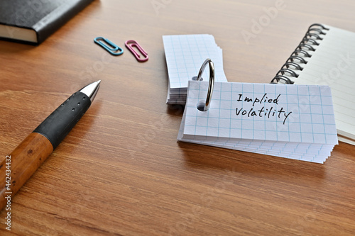 There is a word book with the word implied volatility written on it with a pen and notebook. photo