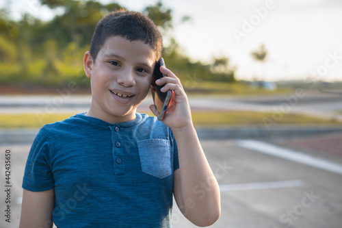 Latino boy talking on cell phone on the street at sunset photo