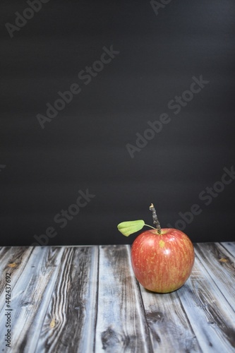 Red apple with a black background and wood table
