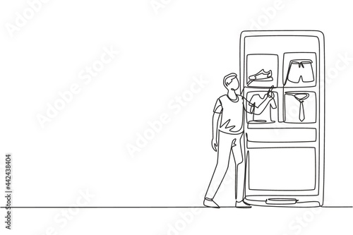 Single one line drawing young man choosing shopping items on a giant smartphone screen. Digital lifestyle with internet and gadgets concept. Continuous line draw design graphic vector illustration