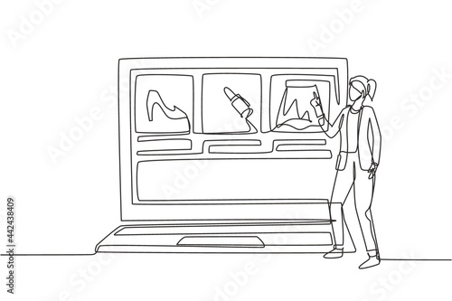 Continuous one line drawing young woman choosing shopping items on a giant laptop screen. Digital lifestyle with internet and gadgets concept. Single line draw design vector graphic illustration