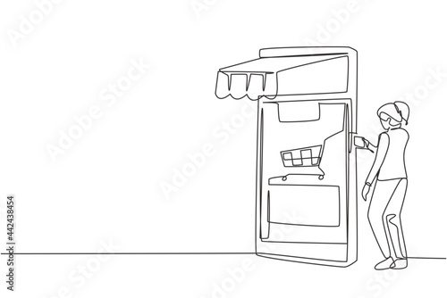 Single one line drawing young woman inserting credit card into canopy smartphone screen with shopping cart. Digital payment concept. Modern continuous line draw design graphic vector illustration