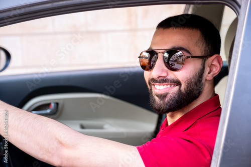 Arabic man driving his car with smile and feeling confident